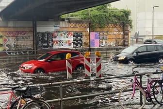 Autos fahren über eine überschwemmte Straße nahe dem S-Bahnhof Yorckstraße.