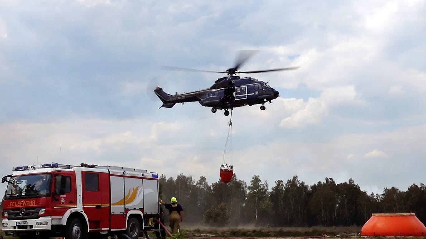 Ein Löschhubschrauber ist in einem Waldstück nahe Jüterbog im Einsatz: Die Lage beim Waldbrand auf dem ehemaligen Truppenübungsplatz bei Jüterbog hatte sich zuletzt wieder "dramatisiert".