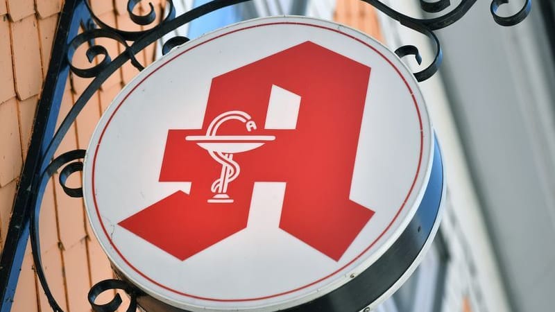 Das Apothekenzeichen hängt an einer Hausfassade (Symbolbild): In NRW haben Apotheken künftig flexibere Öffnungszeiten.