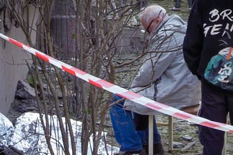Ein Mann sitzt vor der Leiche seiner Tochter, die von Folie abgedeckt, ist in Kiew