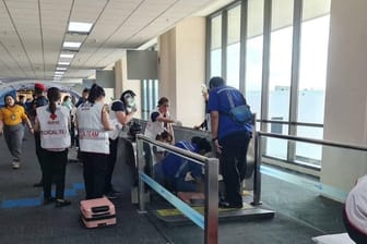Rettungskräfte stehen an dem Laufband am Flughafen in Bangkok, an dem das Bein einer Frau eingezogen wurde.