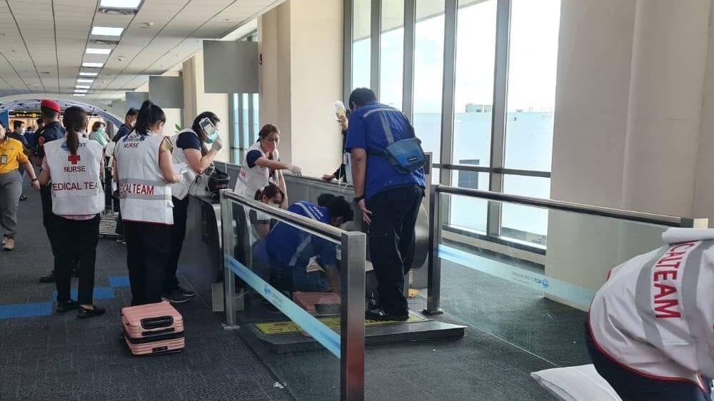 Rettungskräfte stehen an dem Laufband am Flughafen in Bangkok, an dem das Bein einer Frau eingezogen wurde.