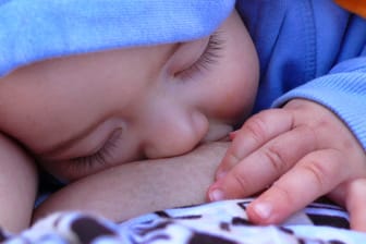 Ein Baby ist beim Stillen eingeschlafen (Symbolfoto): Für stillende Mütter gibt es arbeitsrechtliche Regelungen.