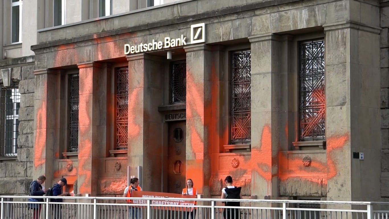 Aktivisten der Gruppe Letzte Generation stehen vor der Deutschen Bank: Sie haben das Gebäude mit Farbe besprüht.