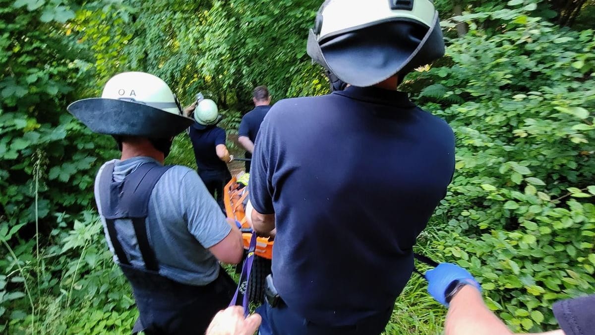 Einsatzkräfte tragen den Verletzten aus dem Wald: Die hohen Temperaturen machten dem Team zu schaffen. Einsatzkräfte tragen den Verletzten aus dem Wald: Die hohen Temperaturen machten dem Team zu schaffen.
