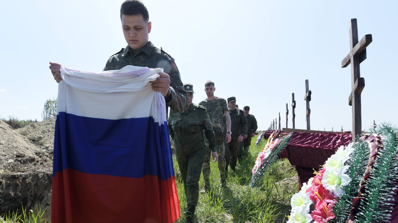 Ein junger Soldat hält die russische Flagge auf einer Beerdigung dutzender Kameraden, die in der besetzten Region Luhansk, im Osten der Ukraine, auf der Seite Russlands gekämpft hatten.