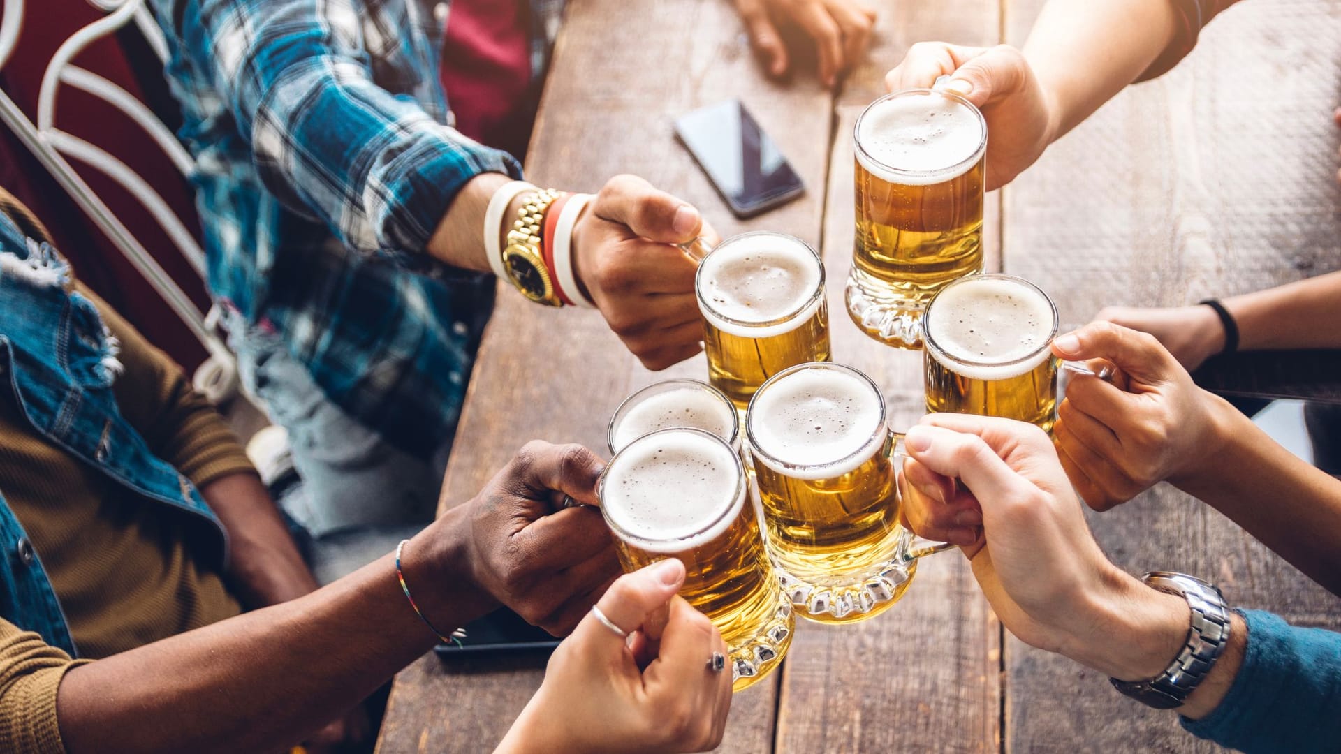 Eine Gruppe von Menschen stößt mit Bier an (Symbolbild): Eine Brauerei in Hannover bringt ein neues Bier auf den Markt.