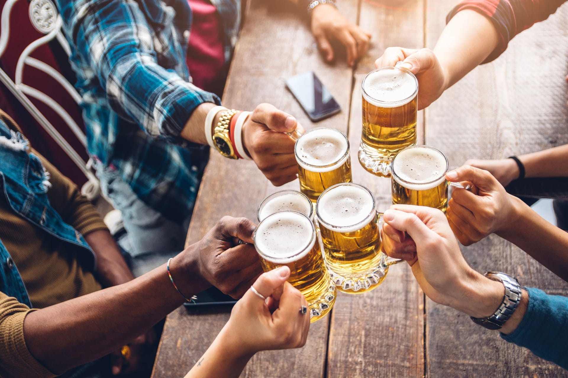 Eine Gruppe von Menschen stößt mit Bier an (Symbolbild): Eine Brauerei in Hannover bringt ein neues Bier auf den Markt.