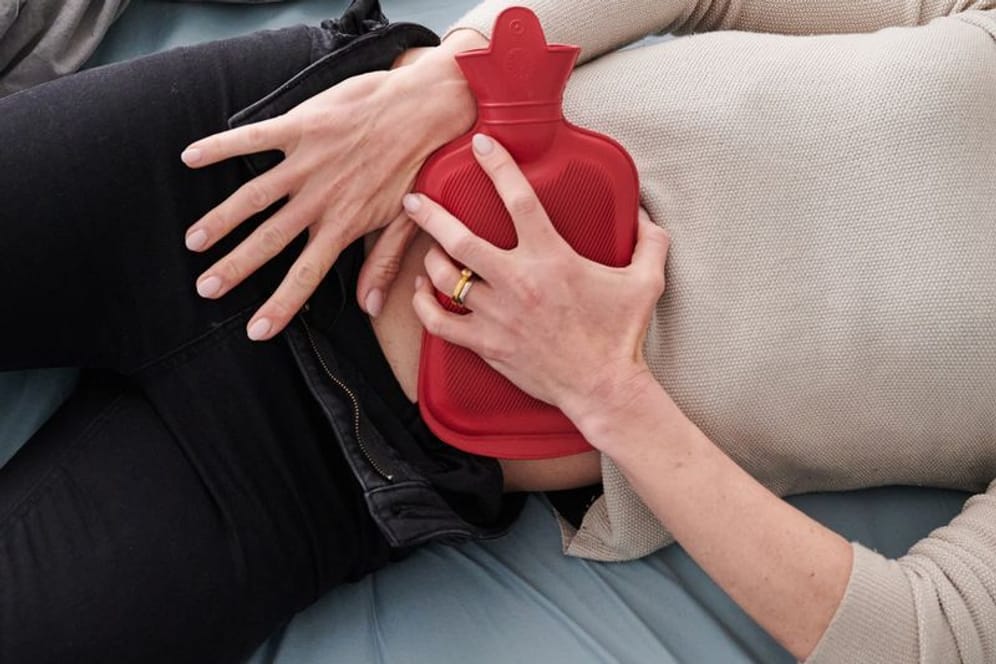 Frau mit Wärmflasche auf dem Unterbauch (Symbolbild): Bei starken Periodenschmerzen dürfen Frauen in Spanien nun Zuhause bleiben.