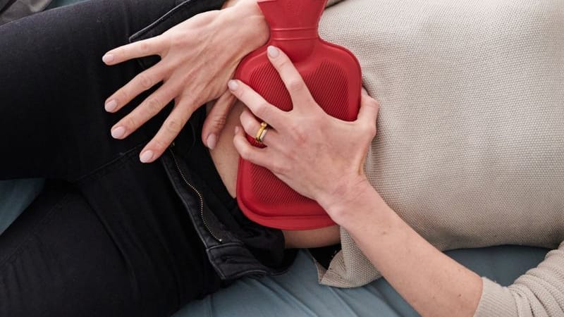 Frau mit Wärmflasche auf dem Unterbauch (Symbolbild): Bei starken Periodenschmerzen dürfen Frauen in Spanien nun Zuhause bleiben.