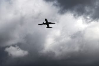 Über einem Flugzeug, das vom Flughafen Düsseldorf startet, türmen sich dunkle Wolken: Der Flugverkehr in Düsseldorf ist durch das Unwetter beeinträchtigt.