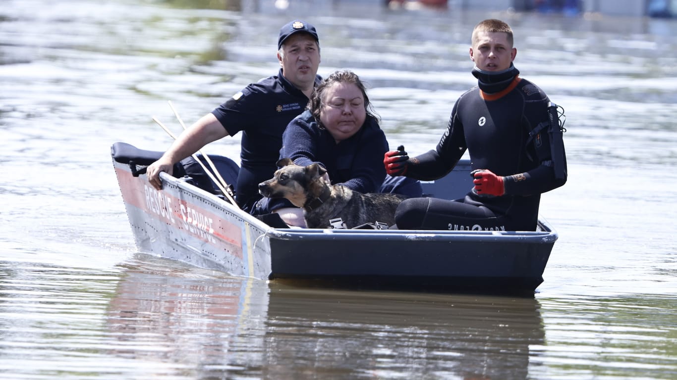Überschwemmung nach Dammbruch in der Ukraine: Helfer retten eine Frau und ihren Hund aus den Fluten bei Cherson.