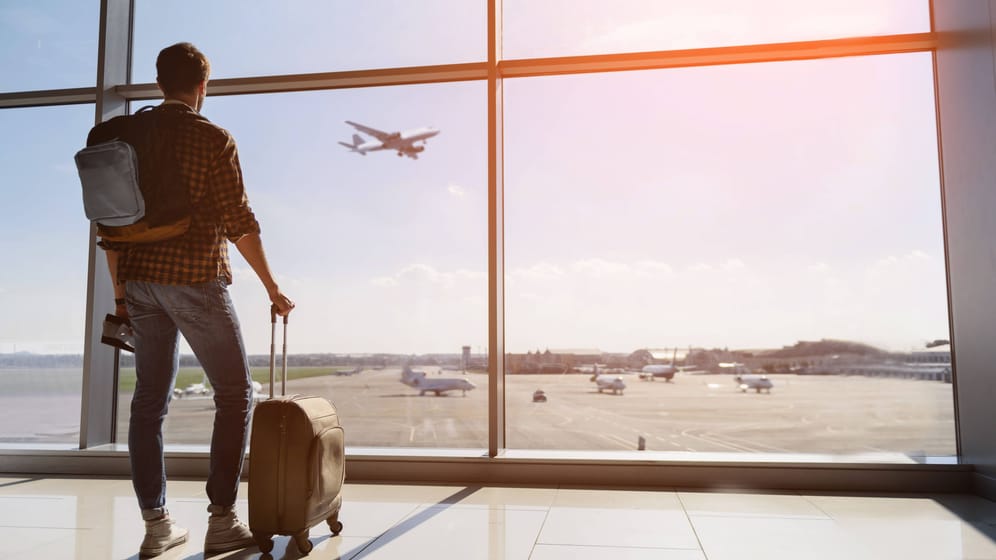 Ein Tourist steht mit Gepäck am Flughafen: Der Rettungsschirm bei einem geplatzten Urlaub ist der Reisesicherungsschein.