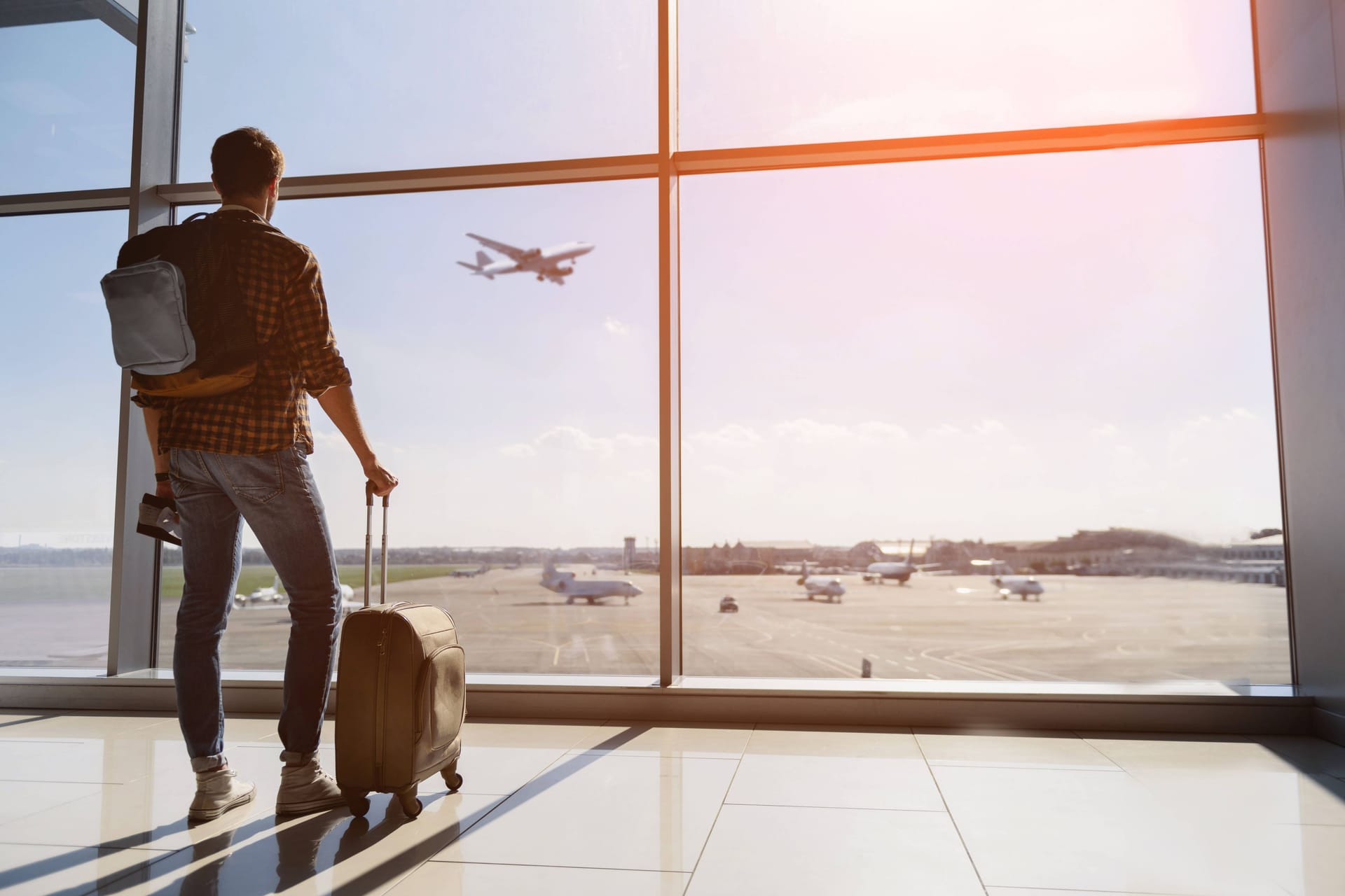 Ein Tourist steht mit Gepäck am Flughafen: Der Rettungsschirm bei einem geplatzten Urlaub ist der Reisesicherungsschein.