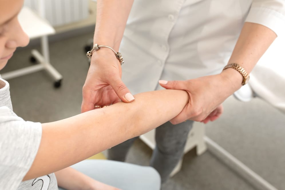 Eine Hautärztin begutachtet den Arm einer Patientin.