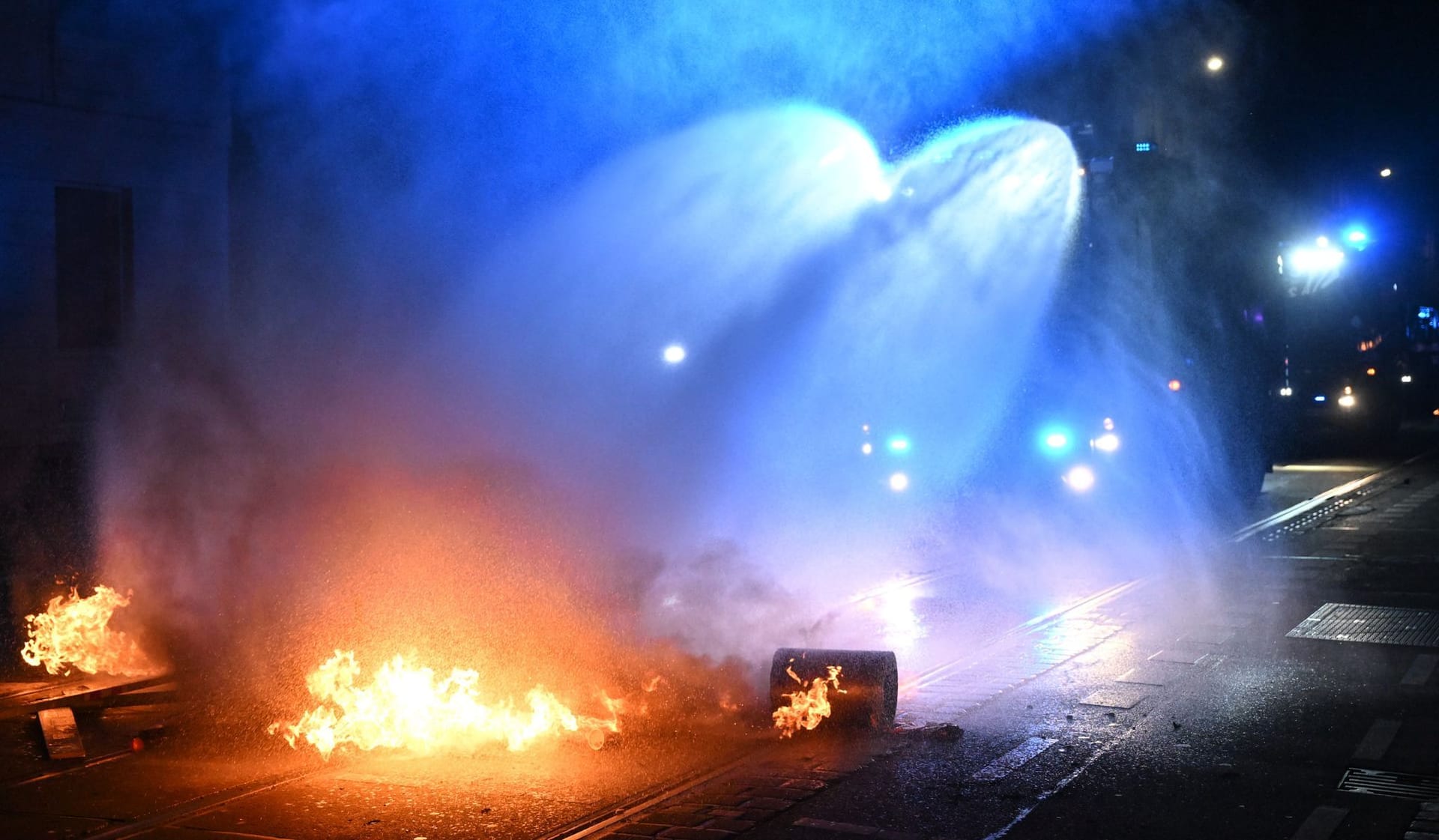Ein Wasserwerfer der Polizei löscht eine brennende Barrikade im Stadtteil Connewitz in Leipzig.