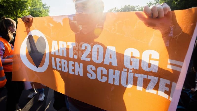 Ein Teilnehmer einer Demonstration der Letzten Generation hält ein Banner.