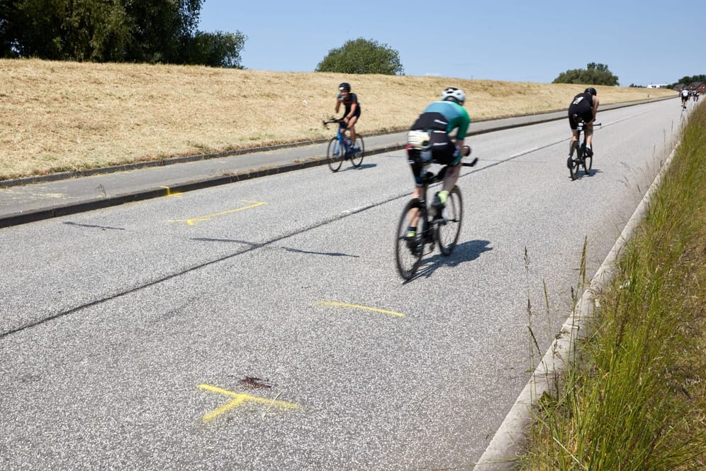 Triathleten fahren auf dem Rad an der Unglücksstelle auf dem Gaueter Hauptdeich vorbei: Hier war ein Motorradfahrer ums Leben gekommen: