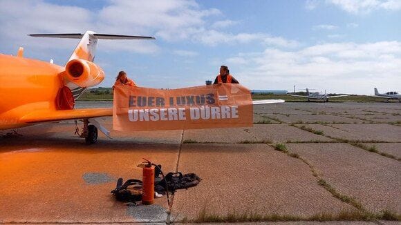 Aktivisten auf der Tragfläche des besprühten Flugzeuges.