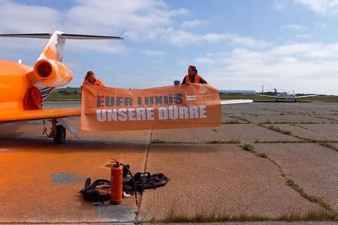 Aktivisten auf der Tragfläche des besprühten Flugzeuges.