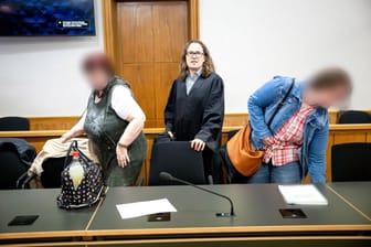 Die Angeklagten stehen mit dem Anwalt Karsten Seeber (M.) im Gerichtssaal vom Landgericht Oldenburg. Der Tatvorwurf lautet Mord.