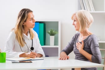 Patientin mit Beschwerden im Brustbereich im Gespräch mit einer Ärztin.