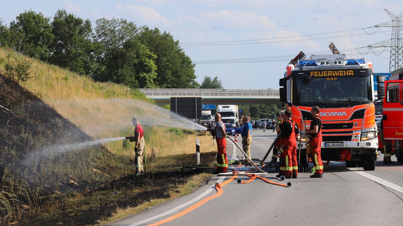 Einsatzkräfte der Feuerwehr löschen den Brand an der A7: Die Autobahn wurde zunächst in beide Richtungen gesperrt.