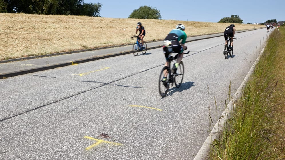 Die Unfallstelle: Triathleten fahren auf dem Rad an dem Ort auf dem Gaueter Hauptdeich vorbei, an dem kurz vorher ein Mensch starb.