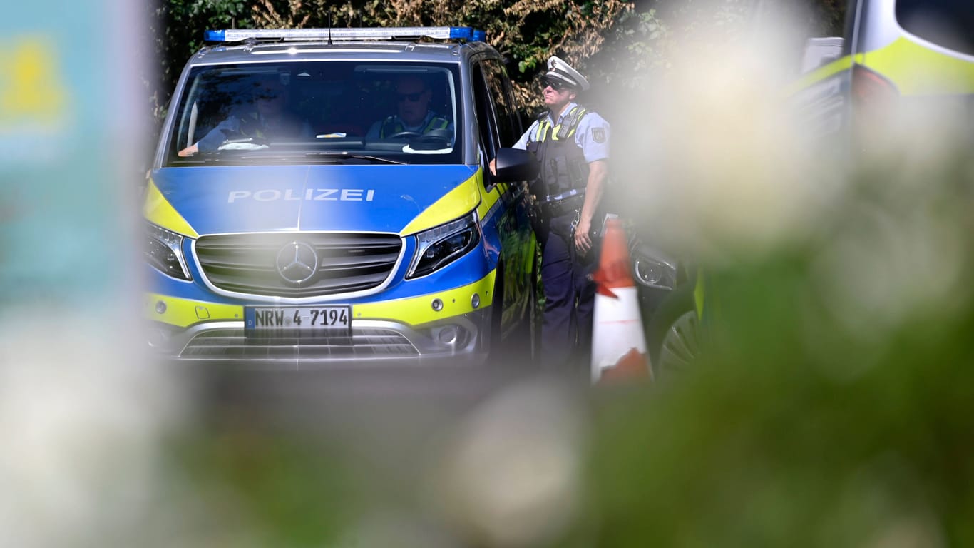 Ein Polizeiauto und Polizisten (Symbolbild): Beamte der Kölner Polizei ermitteln im Fall eines schwerverletzten Kölners in Nippes.