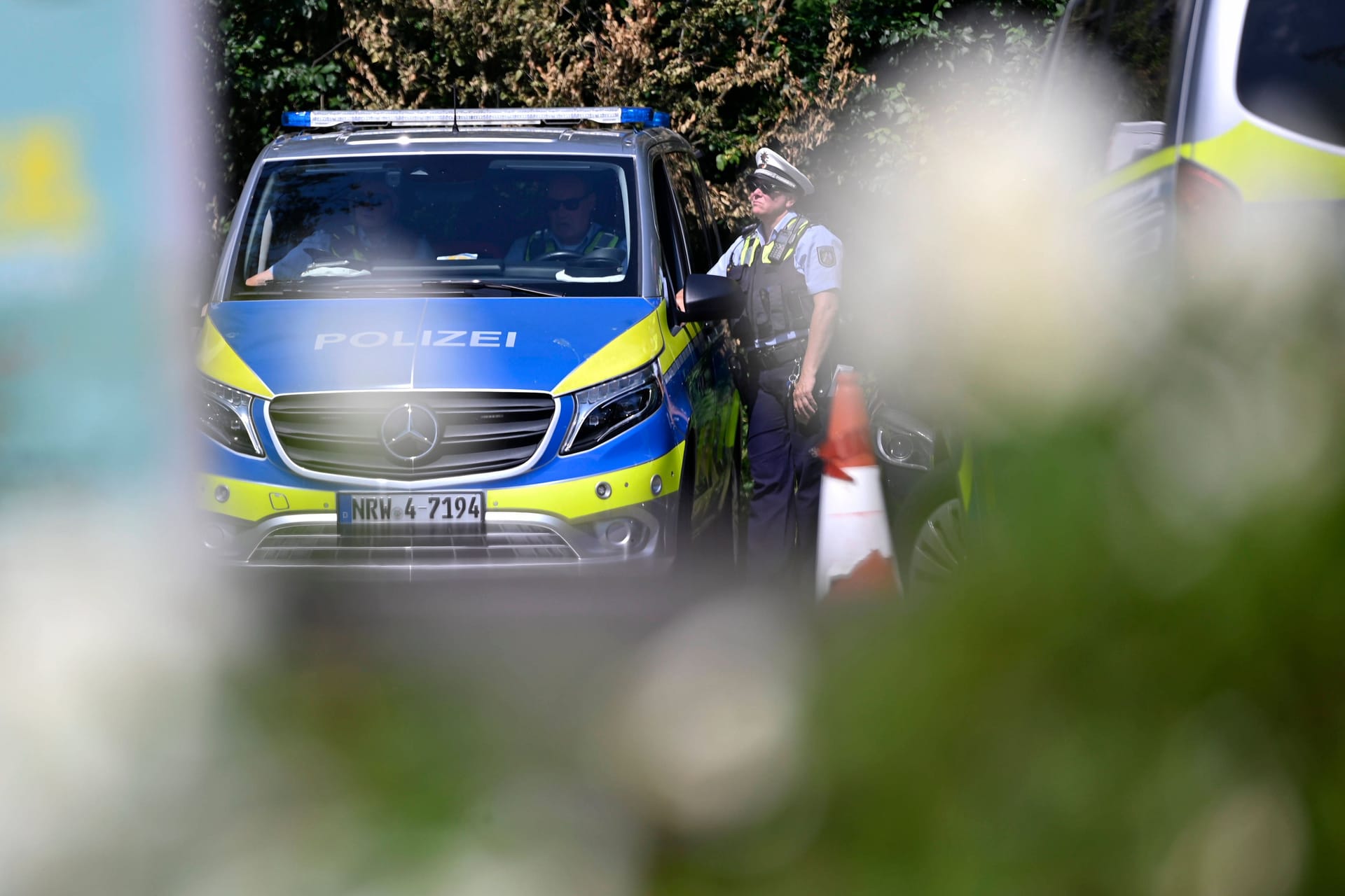 Ein Polizeiauto und Polizisten (Symbolbild): Beamte der Kölner Polizei ermitteln im Fall eines schwerverletzten Kölners in Nippes.
