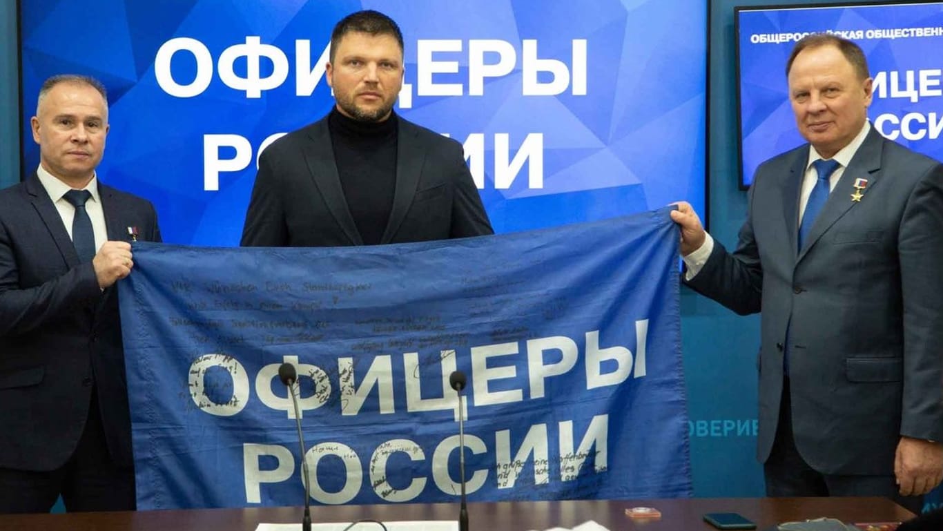 "Standhaftigkeit für Euren Kampf": Eremenko übergibt eine Fahne der "Offiziere Russlands" mit Wünschen aus Deutschland für die Ukraine-Front.
