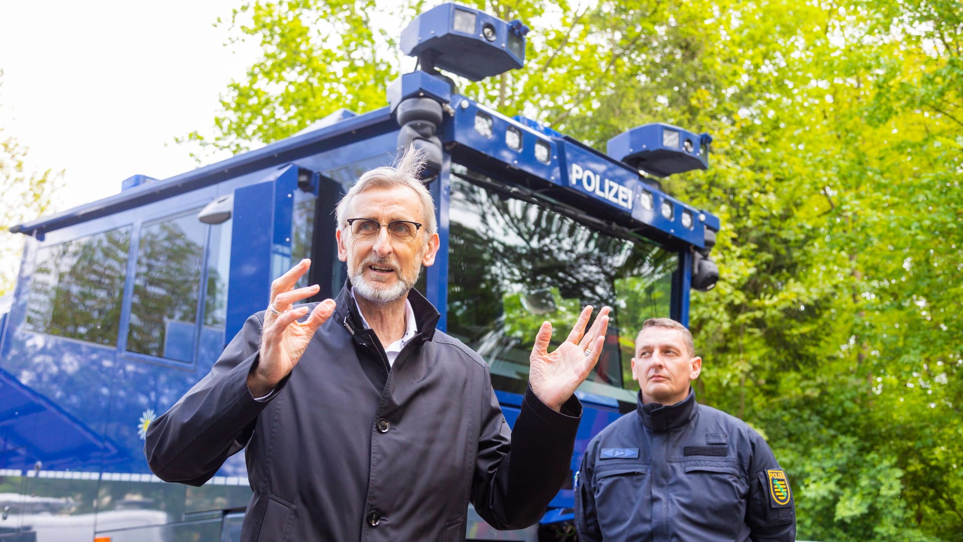 Armin Schuster vor einem Wasserwerfer (Archivbild):