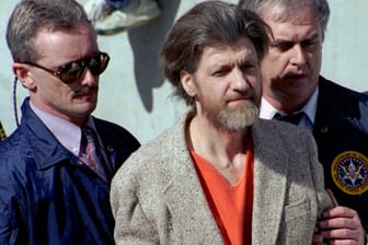 Ted Kaczynski wird 1996 auf dem Weg aus einem Gerichtsgebäude von Ermittlern geführt: Nach mehr als 25 Jahren ist der als "Unabomber" bekannte Attentäter nun in Haft verstorben.