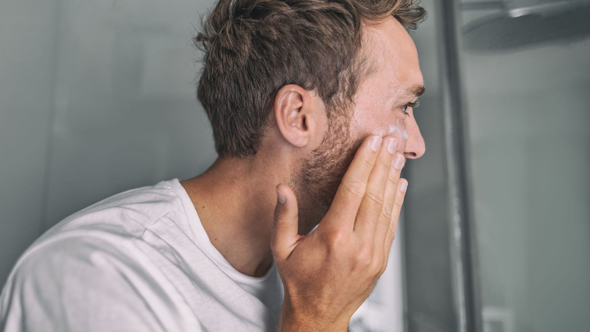 Mann cremt sich das Gesicht ein