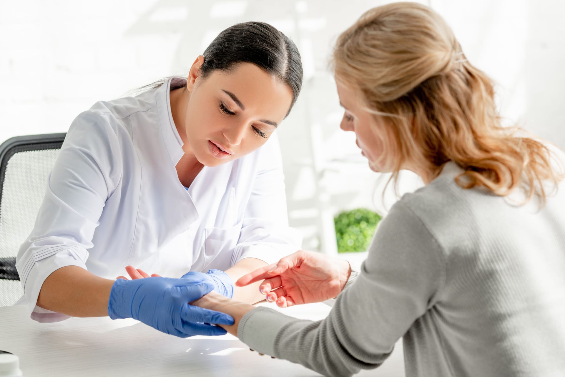 Hautärztin untersucht das Handgelenk einer Frau