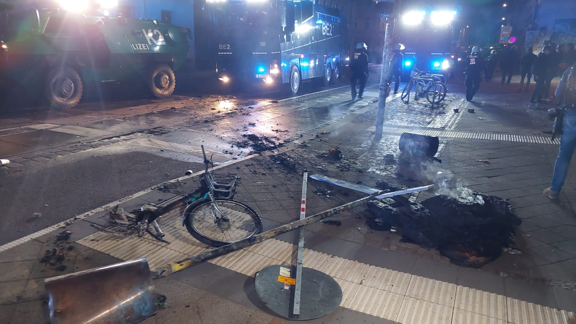 Demolierte Verkehrsschilder und ein zerstörtes Fahrrad liegen am Boden in Connewitz.