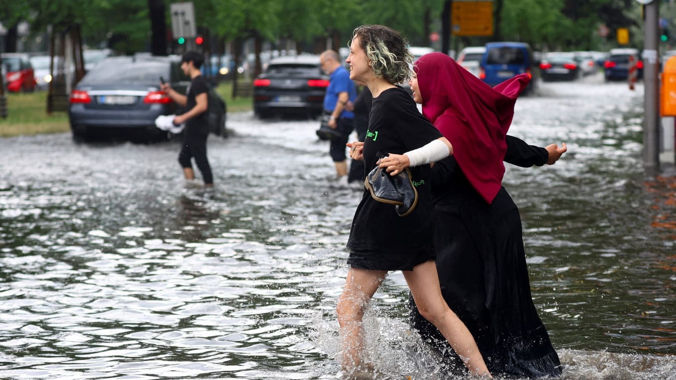 Menschen laufen über eine überflutete Straße: Insbesondere Charlottenburg und Schöneberg hat das Unwetter heimgesucht.