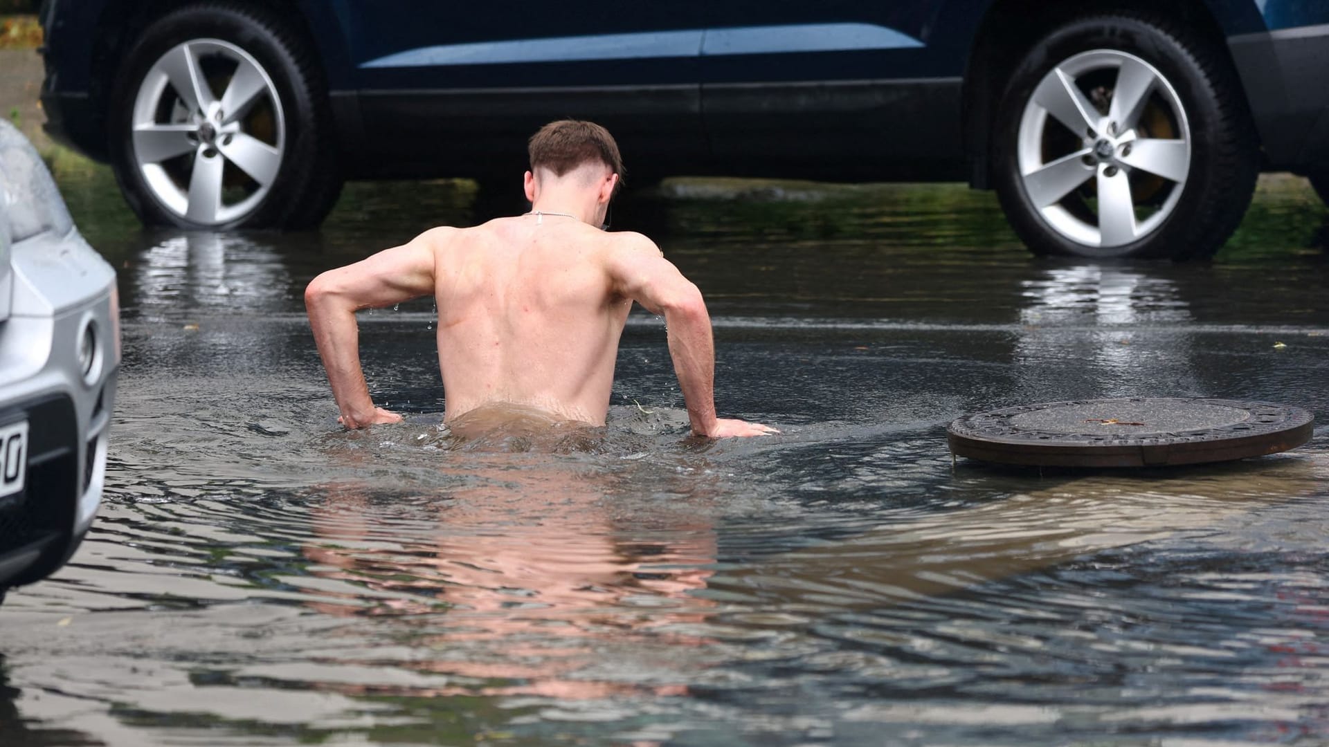 Der Mann im Kanalisationsabstieg: Der schwere Gullideckel, möglicherweise von den Wassermassen hochgedrückt, liegt daneben.