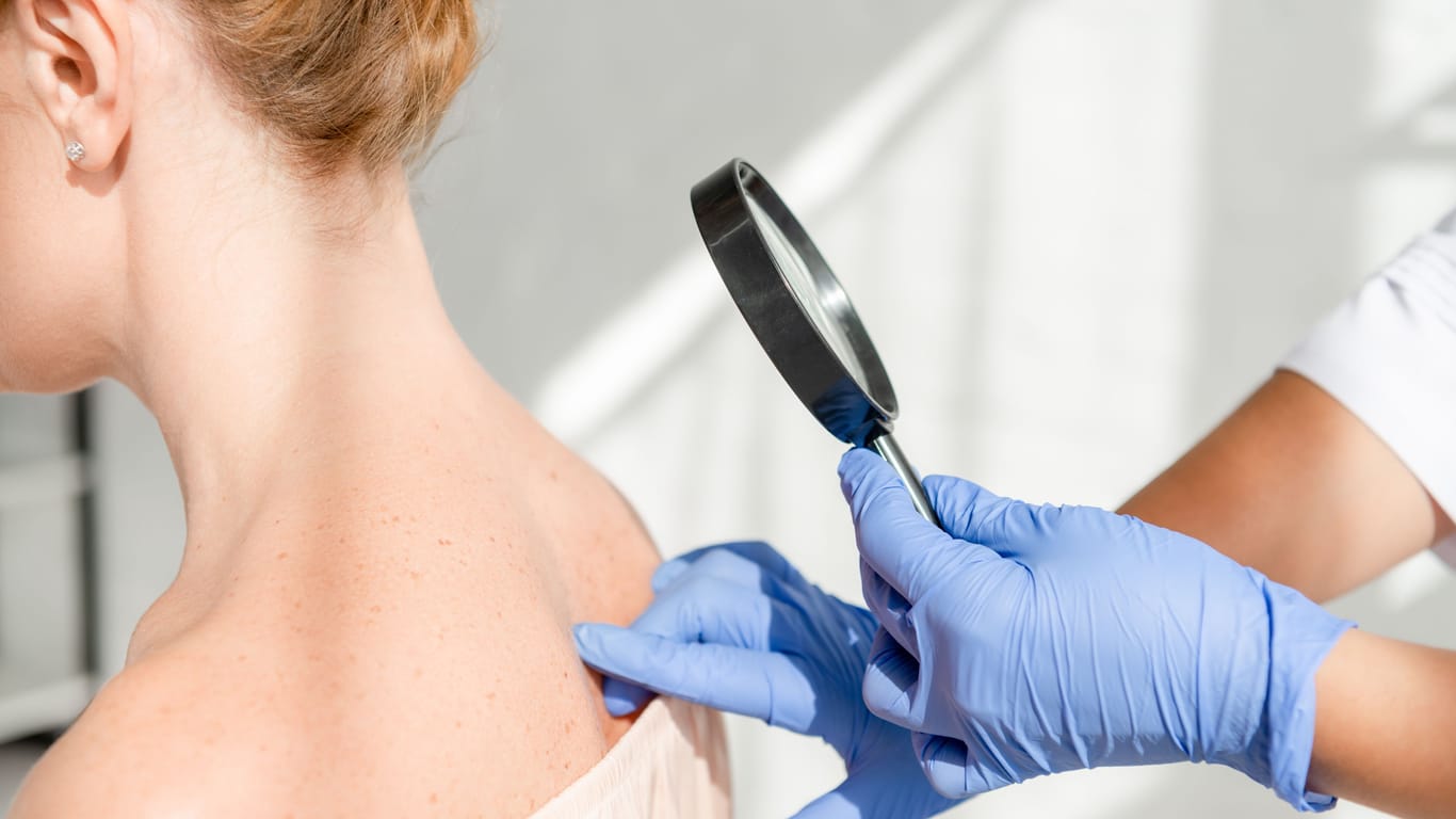 Hautärztin untersucht den Rücken einer Frau