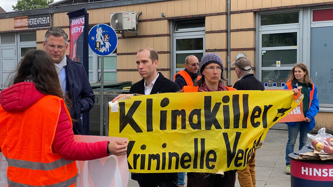 Aktivisten posieren mit Spruchbändern neben den CDU-Politikern: Fünf Personen haben den Stand von Dennis Thering für weniger als 30 Minuten besucht.