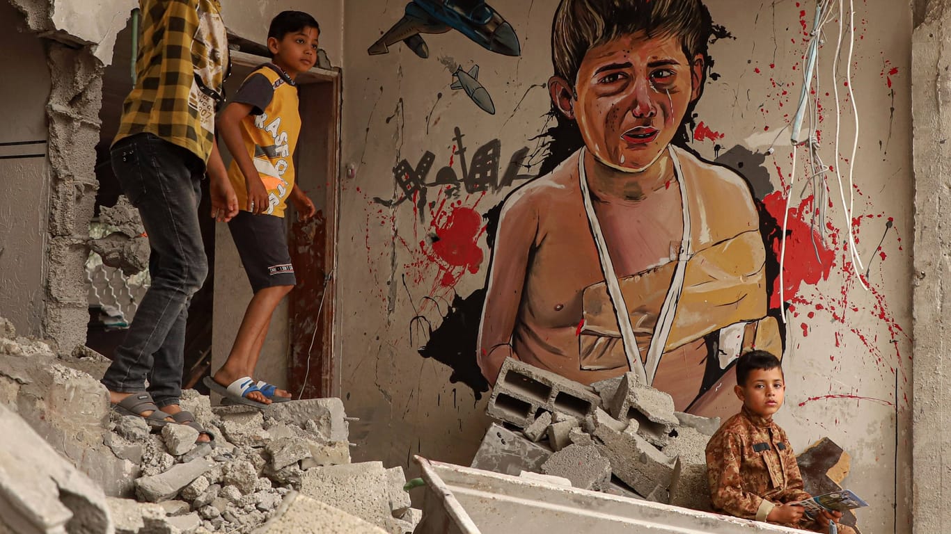 Palästinensische Kinder spielen in einem zertrümmerten Haus nahe eines Flüchtlingscamps im Gazastreifen: Die Zunahme von bewaffneten Konflikte, Hungersnöten und Extremwettern wie Dürren treibt immer mehr Menschen weltweit zur Flucht.