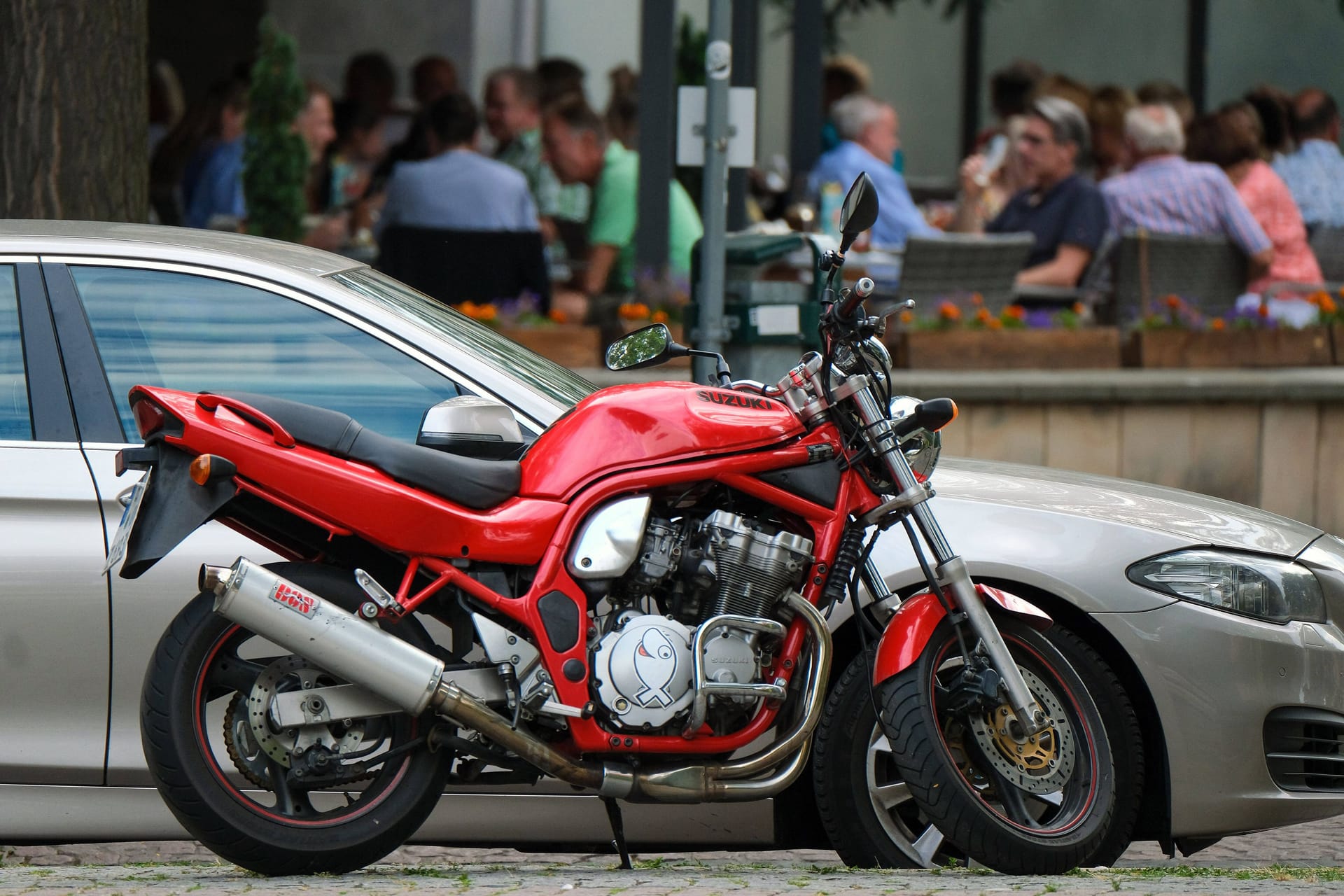 Ein Motorrad neben einem geparkten Auto (Symbolbild): Einer der Fahrer versuchte noch sein Glück dabei, den Beamten zu entkommen.