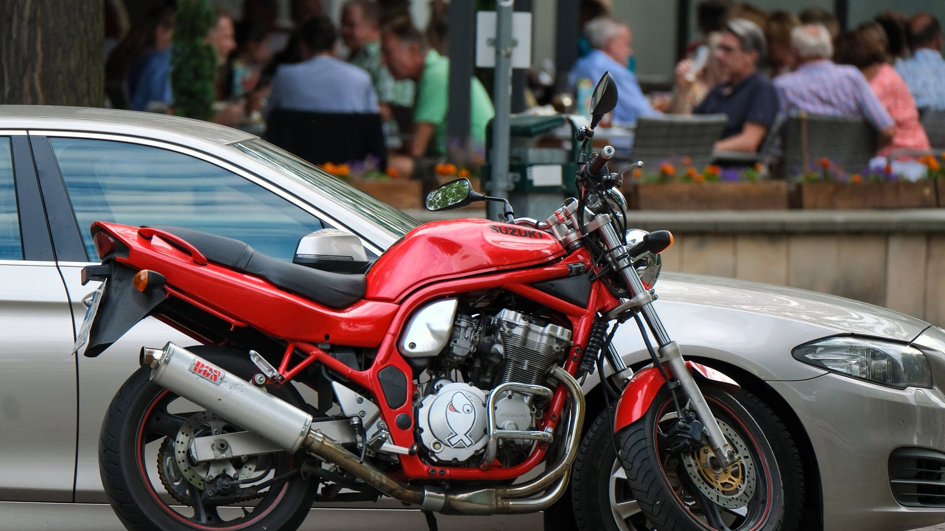 Ein Motorrad neben einem geparkten Auto (Symbolbild): Einer der Fahrer versuchte noch sein Glück dabei, den Beamten zu entkommen.