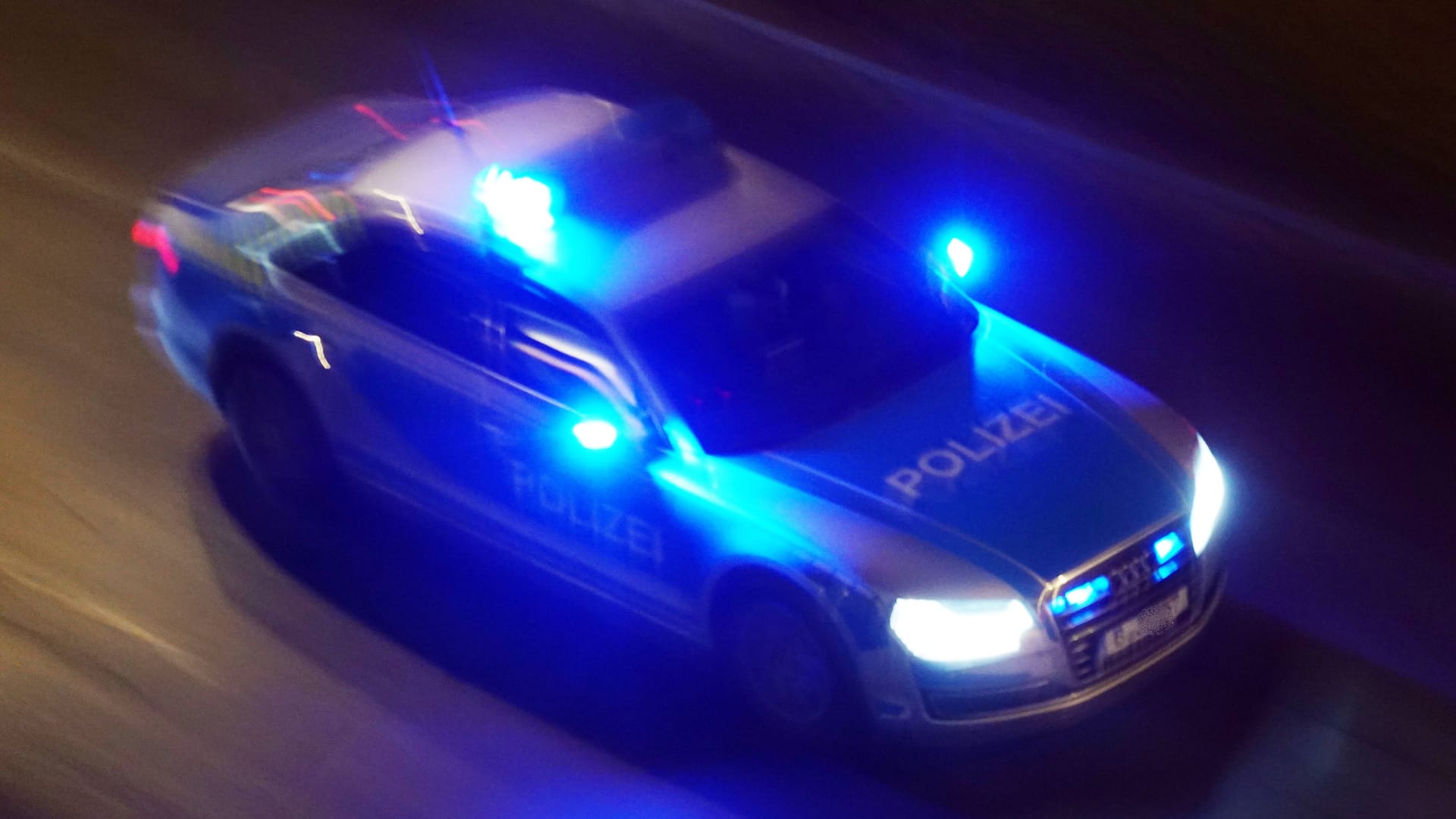 Polizeiauto fährt mit Blaulicht durch die Nacht (Symbolbild): Die vier Tatverdächtigen werden mit Fotos gesucht.