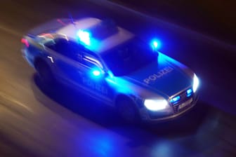 Polizeiauto fährt mit Blaulicht durch die Nacht (Symbolbild): Die vier Tatverdächtigen werden mit Fotos gesucht.