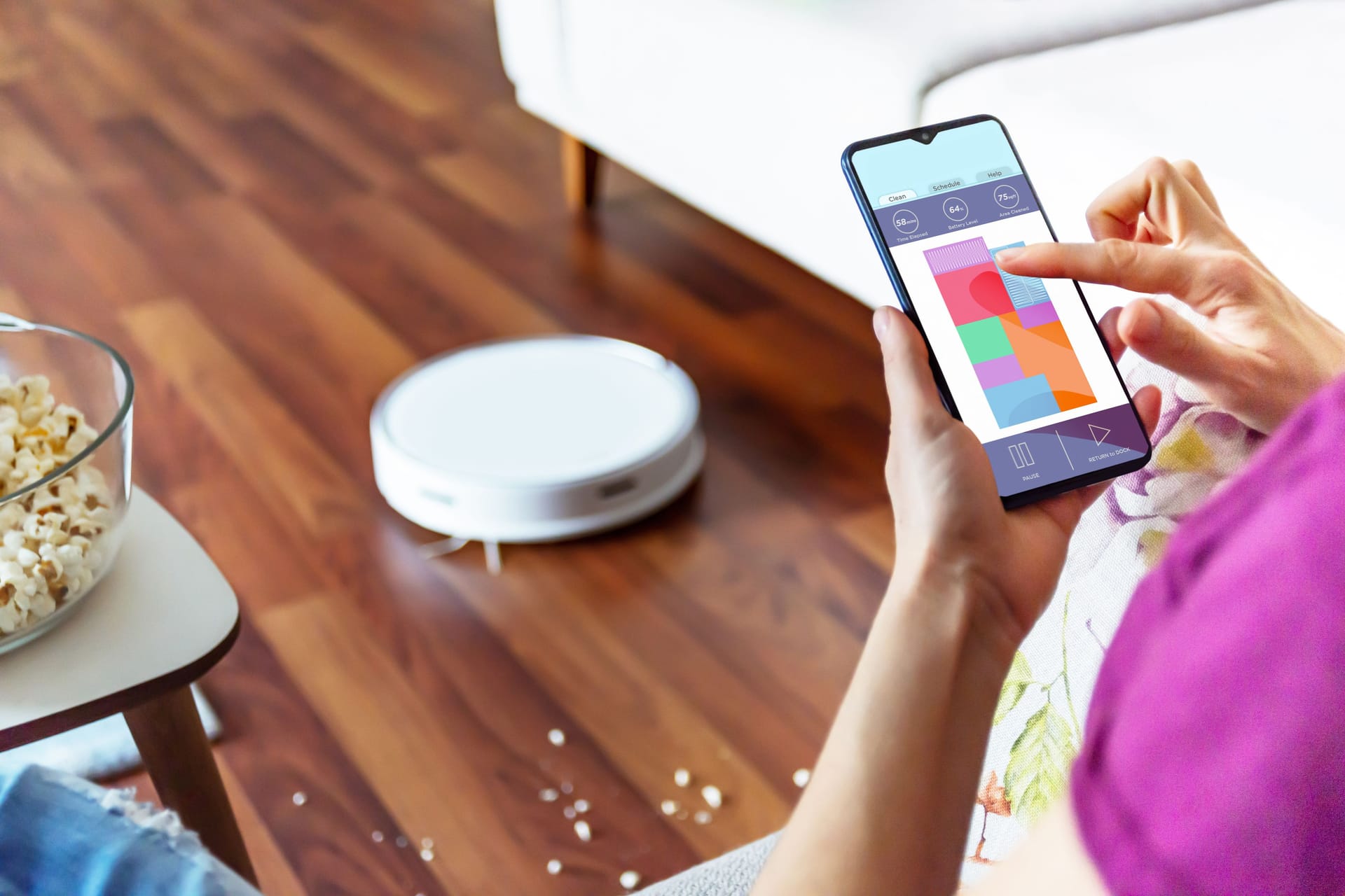 Eine Person bedient einen Staubsauger per App: