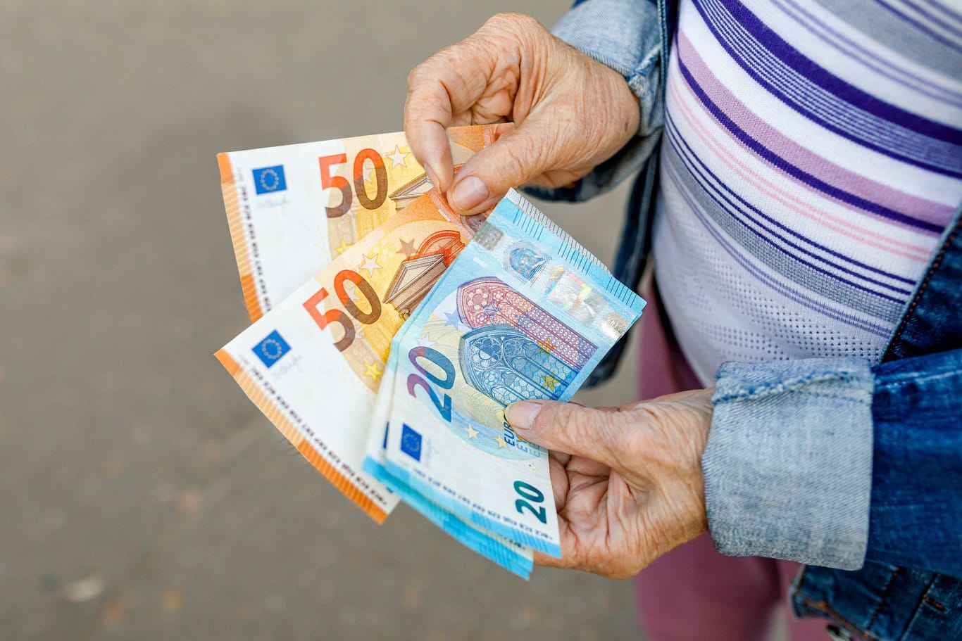 Rentnerin hält Euroscheine (Symbolbild): Rund 80 Prozent der Berechtigten lassen sich den Entlastungsbeitrag der Pflegeversicherung entgehen.