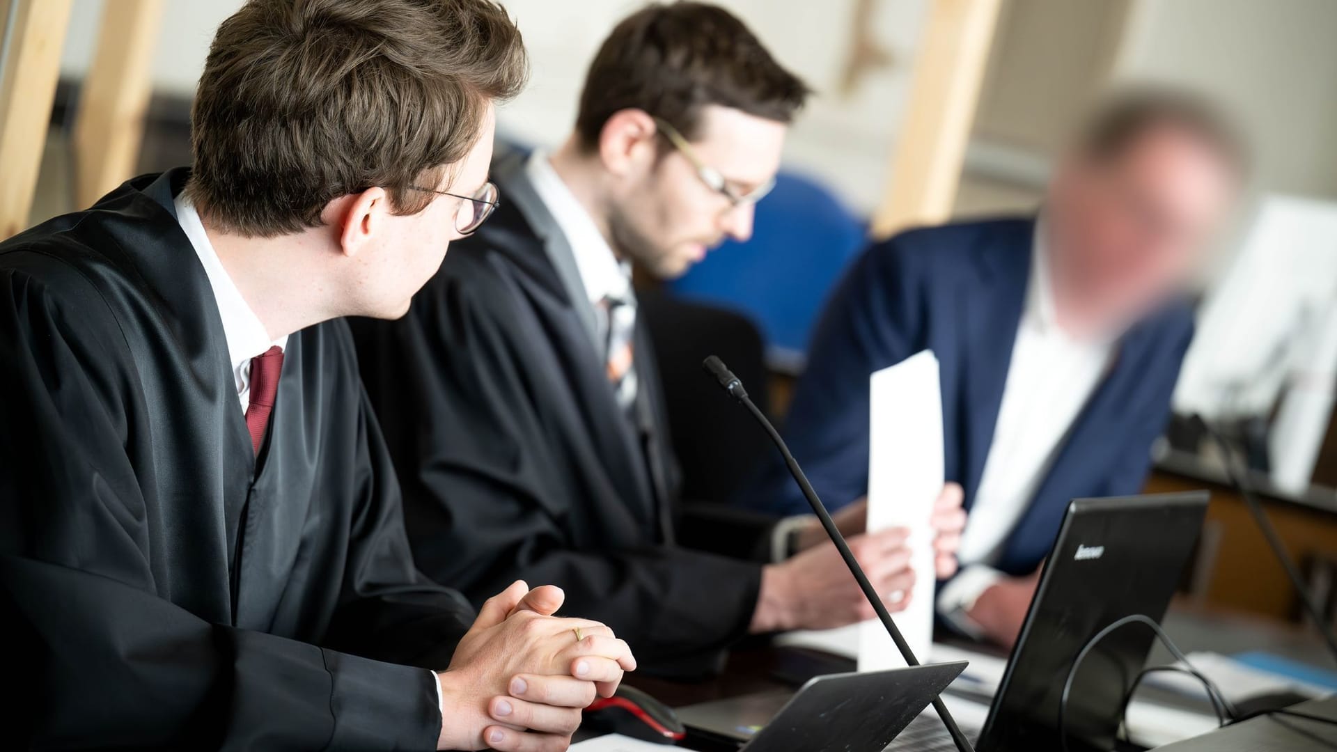 Der Angeklagte (rechts) sitzt vor Prozessbeginn mit seinen Anwälten im Gerichtssaal: Der Mediziner soll eine Hirnblutung nicht erkannt haben. Der Angeklagte (rechts) sitzt vor Prozessbeginn mit seinen Anwälten im Gerichtssaal: Der Mediziner soll eine Hirnblutung nicht erkannt haben.