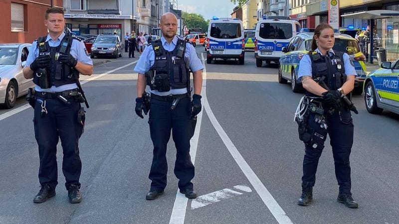 Polizisten stehen am Rande einer Massenschlägerei und riegeln eine Straße ab.