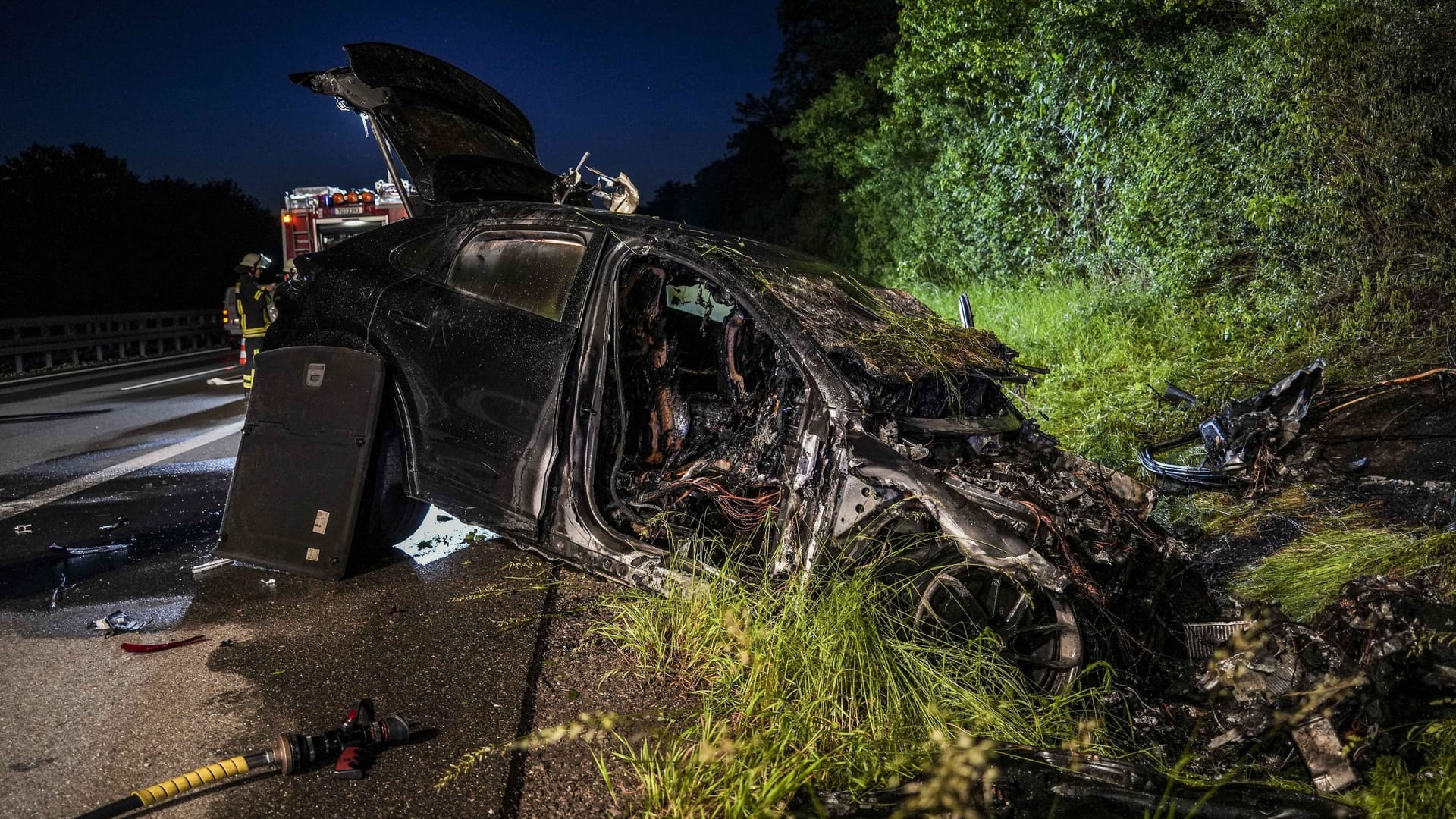 Der komplett ausgebrannte Porsche liegt am Straßenrand: Die Löscharbeiten gestalteten sich für die Feuerwehrleute schwierig.